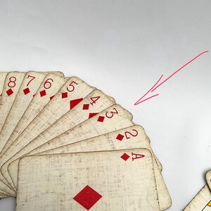 May include: A fan of antique playing cards featuring the suit of diamonds. The cards have a distressed, vintage look with red diamond symbols and numbers. The Ace, 2, 3, 4, 5, 6, 7, and 8 of diamonds are visible.