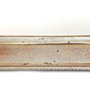 Op de afbeelding: Een rechthoekig metalen dienblad met een doffe zilver- en messingafwerking. Het blad is voorzien van ingewikkelde bloemengravures in het midden en langs de rand, met sierlijke, gebogen handvatten aan beide zijden en een geschulpte rand.