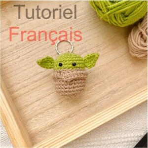 Peut inclure: Un porte-clés en crochet vert et marron en forme de personnage de la franchise Star Wars. Le porte-clés est muni d'un anneau de clé argenté. Le texte "Tutoriel Français" est visible en arrière-plan.