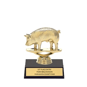 May include: Gold pig trophy on a black base with a gold stand. The base has a gold plaque that reads "1st Place Entry Pork BBQ Division Fairhaven County Fair".