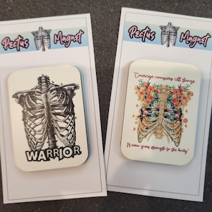 May include: Two white square magnets with a ribcage design. One magnet features a black and white ribcage with the word "WARRIOR" below it. The other magnet features a colorful ribcage with flowers and the text "Courage conquers all things. It even gives strength to the body."