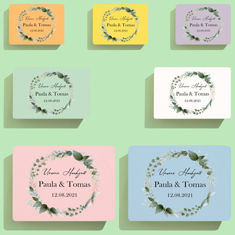 Puede incluir: Seis tarjetas de diferentes colores con una corona de hojas verdes y el texto "Unsere Hochzeit Paula & Tomas 12.08.2021" en negro.