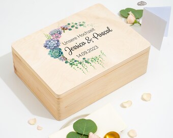 Può includere: Una scatola di legno con un coperchio, decorata con un motivo floreale ad acquerello di piante grasse e verde. Il coperchio ha la scritta "Unsere Hochzeit Jessica & Pascal 14.09.2023" stampata su di esso.
