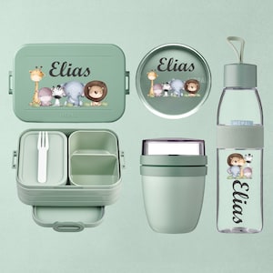Puede incluir: Un conjunto de accesorios para el almuerzo verdes, que incluyen una lonchera, un recipiente redondo, un tarro de comida y una botella de agua. Cada artículo presenta un diseño de animales de safari y el nombre "Elias".