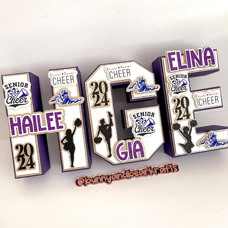 May include: Purple, gold and white letter blocks spelling "HAILEE GIA ELINA" with cheerleading pom-poms, silhouettes and the text "Senior Cheer 2024" on each block.