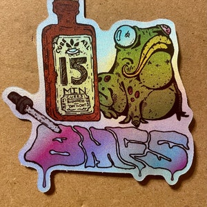 Può includere: Un adesivo con una rana di cartone animato, una bottiglia etichettata "15 Min Cures Sickness", e la parola "BAMES" in un font colorato e gocciolante.