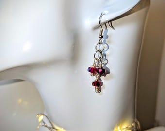 May include: Silver dangle earrings with a chain and three red crystal beads.