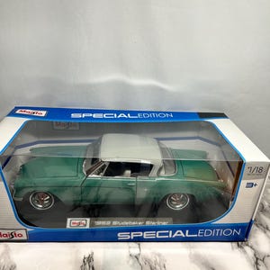 May include: A green and white 1953 Studebaker Starliner model car in its original packaging. The model is a 1/18 scale diecast metal car. The packaging reads "Special Edition" and features the Maisto logo.