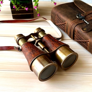K&ouml;nnte beinhalten: Messing-Fernglas mit Holzmaserung und Lederriemen. Das Fernglas hat einen Vintage-Look und ist perfekt f&uuml;r die Vogelbeobachtung oder andere Outdoor-Aktivit&auml;ten.