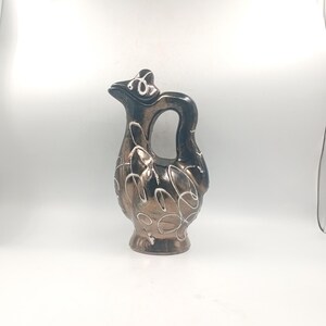 Peut inclure: Pichet décoratif en céramique de couleur bronze avec des motifs tourbillonnants blancs. Le pichet a une anse et un bec verseur. Le design est élégant et vintage. Idéal pour la décoration.