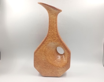 Pode incluir: Um vaso de cerâmica castanho texturizado com um design angular único. O vaso apresenta um bico curvo e uma abertura circular na lateral. O vaso tem um aspeto salpicado e uma base geométrica. O vaso tem cerca de 30 cm de altura.