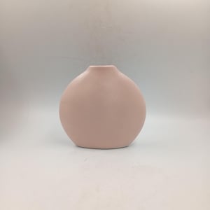Peut inclure: Un vase en céramique rose pâle avec un corps arrondi et un col étroit. Le vase a une finition lisse et mate et un design simple. Le vase mesure environ 18 cm de haut et 15 cm de large.