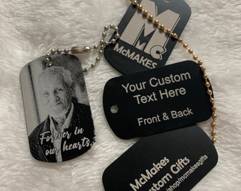 Könnte beinhalten: Vier schwarze Metall-Hundemarken mit silbernen Ringen und einer goldenen Kette. Die Marken sind mit dem Text "McMakes", "Your Custom Text Here Front & Back", "Forever in our hearts" und "McMakes Custom Gifts etsy.com/shop/mcmakesgifts" graviert.