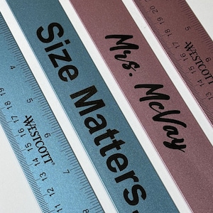 Pode incluir: Close-up de quatro réguas de metal com texto preto. As réguas são em tons de azul e malva. Uma régua diz "Size Matters". Outra diz "Mrs. McVay". Cada régua tem medidas em polegadas.