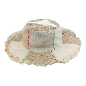 Könnte beinhalten: Ein Patchwork-Eimerhut mit ausgefranstem Rand. Der Hut hat eine Mischung aus beigen, weißen und braunen Stoffen mit farbigen Nähten in Rot, Grün und Lila. Der Hut ist für Sonnenschutz und Freizeitkleidung konzipiert.