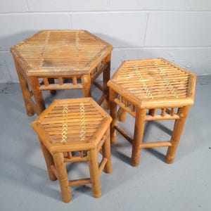May include: A set of three bamboo side tables. Each table has a hexagonal top made of bamboo slats with decorative stitching. The tables are different sizes, with the largest measuring approximately 51 cm wide.