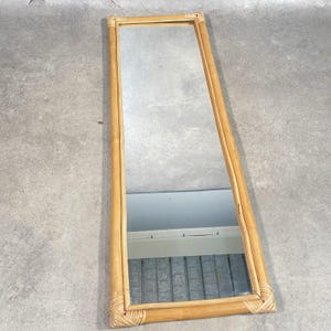 May include: A rectangular full-length mirror featuring a light brown natural bamboo frame. The frame is constructed from multiple bamboo poles joined at the corners with woven bamboo detailing, surrounding a clear, reflective glass mirror surface.