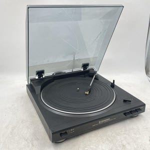May include: A black Pioneer PL-J2500 stereo full automatic turntable with a clear, hinged dust cover. The device features a circular platter, a straight tonearm with a cartridge, and control buttons on the front panel for operation and speed.