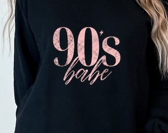 May include: Black sweatshirt with a pink graphic that says "90's babe" in a distressed font.