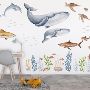 May include: A set of ocean-themed wall decals featuring a variety of sea creatures, including whales, sharks, dolphins, and sea turtles. The decals are painted in a watercolor style and are perfect for adding a touch of whimsy to any room.