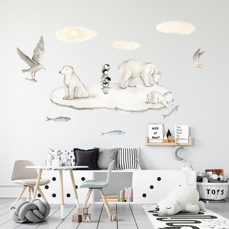 May include: A watercolor illustration of a polar bear family on an iceberg with penguins and seagulls. The illustration is printed on a white wall in a child's room. The room also features a white table with two chairs, a white bench with black and white striped pillows, and a white shelf with a sign that reads "Wild at Heart".