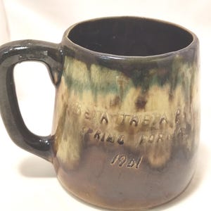 May include: A brown ceramic mug with a green and brown glaze. The mug has a handle and the text "Beta Theta Pi Spring Formal 1981" on the side.
