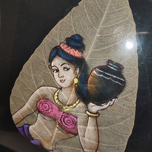May include: A painting of a woman carrying a pot on a dried leaf. The woman is wearing a pink top, a gold necklace, and a blue head scarf. The leaf is beige and has a detailed vein pattern.