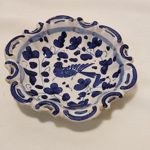 May include: A white ceramic dish with a blue and white floral design and a bird in the centre. The dish has a scalloped edge.