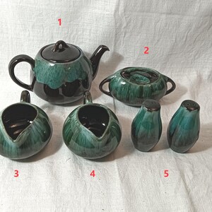 Könnte beinhalten: Ein Keramik-Teeservice mit türkisfarbener und brauner Glasur. Das Set beinhaltet eine Teekanne, eine Zuckerdose, einen Sahnekännchen und Salz- und Pfefferstreuer. Die Teekanne hat einen Deckel und einen Griff. Sahnekännchen und Zuckerdose haben Griffe.