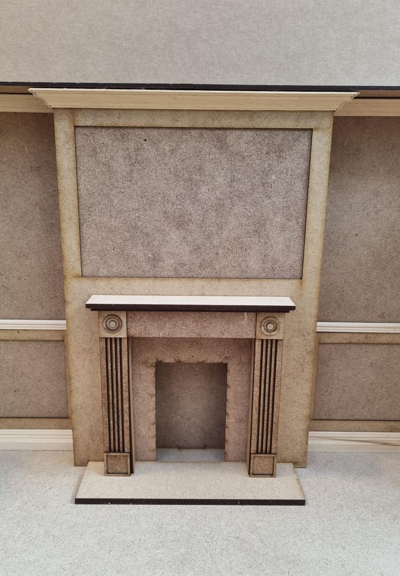 May include: A beige wooden fireplace mantel with a black trim and a rectangular opening for a fire. The mantel is set against a beige wall.