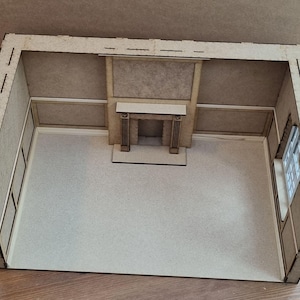 May include: A miniature wooden room with a fireplace and a window. The room is made of light brown wood and has a simple design.