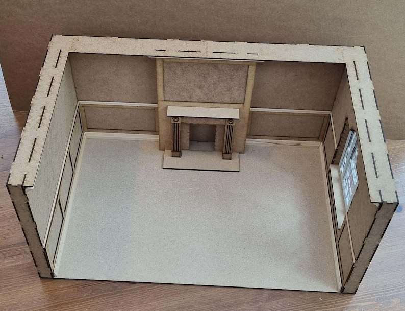May include: A miniature wooden room with a fireplace and a window. The room is made of light brown wood and has a simple design.