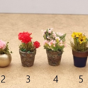 Pode incluir: Pequenas plantas em vasos em v&aacute;rios estilos. Inclui uma flor rosa num vaso dourado, flores vermelhas num vaso texturizado e flores amarelas num vaso azul e castanho. A imagem tamb&eacute;m mostra uma m&atilde;o segurando uma planta de lavanda.