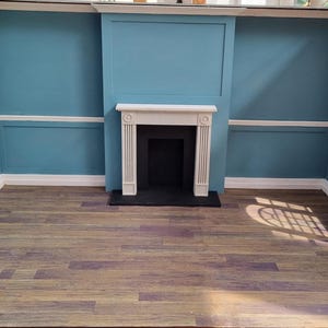May include: A white fireplace with a black hearth in a room with blue walls and wood floors.