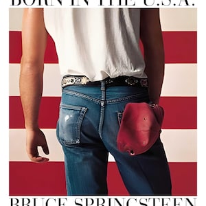 May include: Image featuring the text "BORN IN THE U.S.A." and "BRUCE SPRINGSTEEN." The image shows a person from the back wearing blue jeans, a white shirt, and a red baseball cap. The background is a red and white striped pattern.