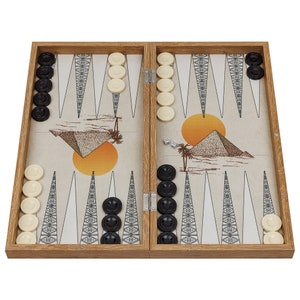 Könnte beinhalten: Ein Backgammon-Spielbrett aus Holz mit Wüstenmotiv. Das Brett ist geöffnet und zeigt schwarze und weiße Spielsteine, Würfel und eine Wüstenszene mit Pyramiden und Palmen.