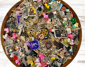 May include: A wooden bowl filled with a variety of colourful charms, including animals, flowers, and geometric shapes. The charms are made of metal, glass, and plastic. Some of the charms have a vintage look, while others are more modern. The bowl is a great way to add a touch of whimsy to any room.