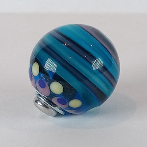 May include: A white ceramic mug with a black handle and the text "But First, Coffee" in a bold, black font. The mug is sitting on a wooden surface. The mug is approximately 4 inches tall.