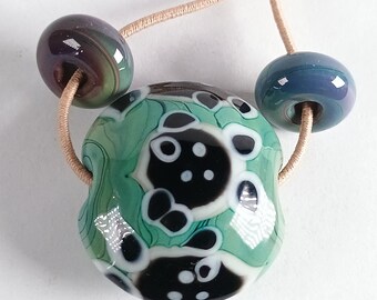 Green lampwork lentil bead with black and white fish detail - Jolene Beads