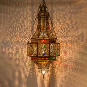 May include: A gold Moroccan lantern with intricate detailing and colorful glass accents hangs from a chain.