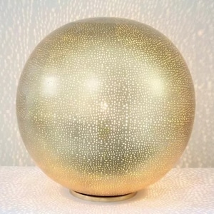 May include: A gold-coloured sphere lamp with a patterned surface. The lamp has a round base and emits a warm glow.