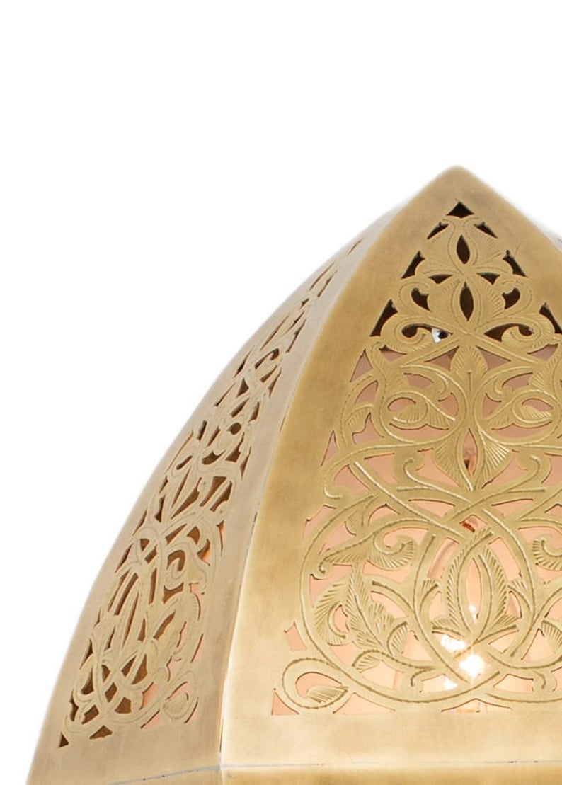 May include: A dome-shaped brass lamp shade featuring intricate laser-cut filigree patterns with swirling floral and vine motifs. The metallic surface has a warm gold tone, and the cutouts reveal a soft, glowing light from within the structure.