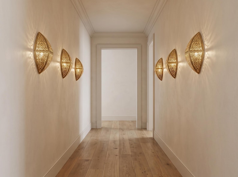 May include: Six gold-toned, semi-circular wall sconces with intricate, perforated cut-out patterns. Each fixture emits a warm, glowing light that casts a starburst effect onto the surrounding wall surfaces in a symmetrical arrangement.