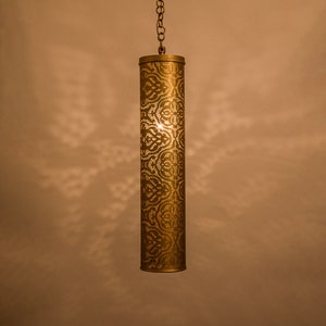 Könnte beinhalten: Eine goldene Pendelleuchte aus Metall mit einem dekorativen, filigranen Muster. Die Leuchte hängt an einer Kette.