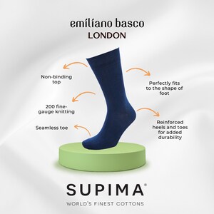 May include: A pair of dark blue socks made with Supima cotton. The socks feature a seamless toe, reinforced heels and toes, and a non-binding top. The socks are displayed on a green platform with the text "SUPIMA" and "WORLD'S FINEST COTTONS" below.