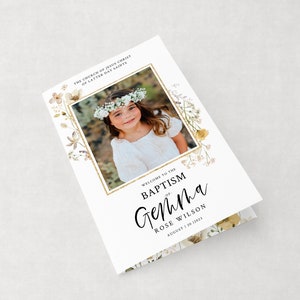 May include: A white card with a floral border and a photo of a young girl wearing a white dress and a flower crown. The text on the card reads "Welcome to the Baptism of Gemina Rose Wilson August 20, 2023".