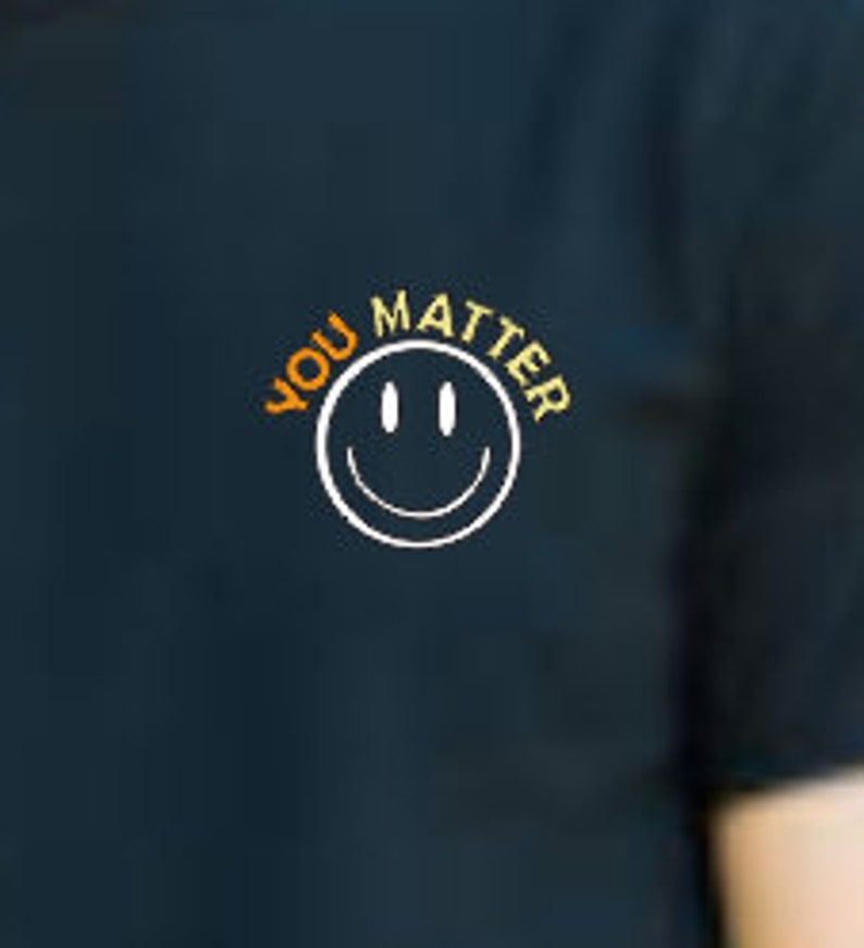 May include: A dark blue t-shirt with the text "YOU MATTER" in orange and yellow lettering, a white smiley face graphic, and a white outline.