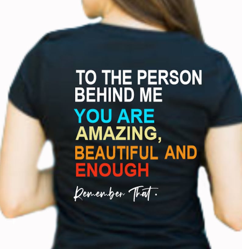 May include: Black t-shirt with the text "To the person behind me, you are amazing, beautiful and enough. Remember that." in colorful text.