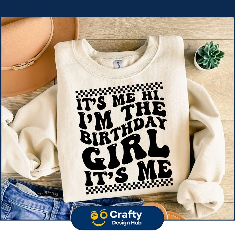 May include: A white sweatshirt with a black graphic that says "It's Me Hi. I'm The Birthday Girl. It's Me." The graphic is surrounded by a black and white checkered border.