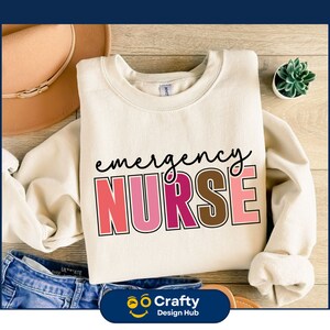 May include: A cream-colored sweatshirt with the text "emergency nurse" in colorful letters. The letters are outlined in black and have a rainbow color scheme.